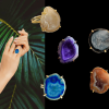 Hand wearing a blue druzy gemstone ring with palm leaves in the background.